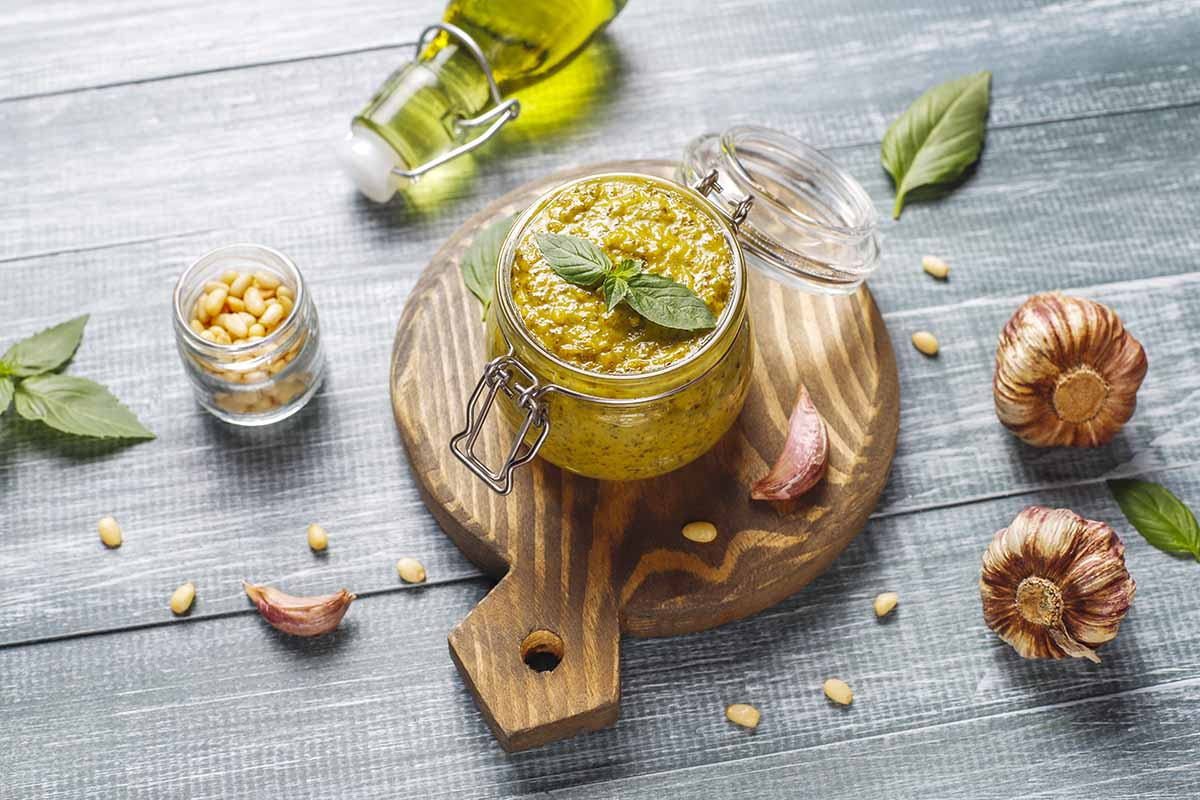 Domowe pesto z pędów czosnku w słoiczku na drewnianej desce